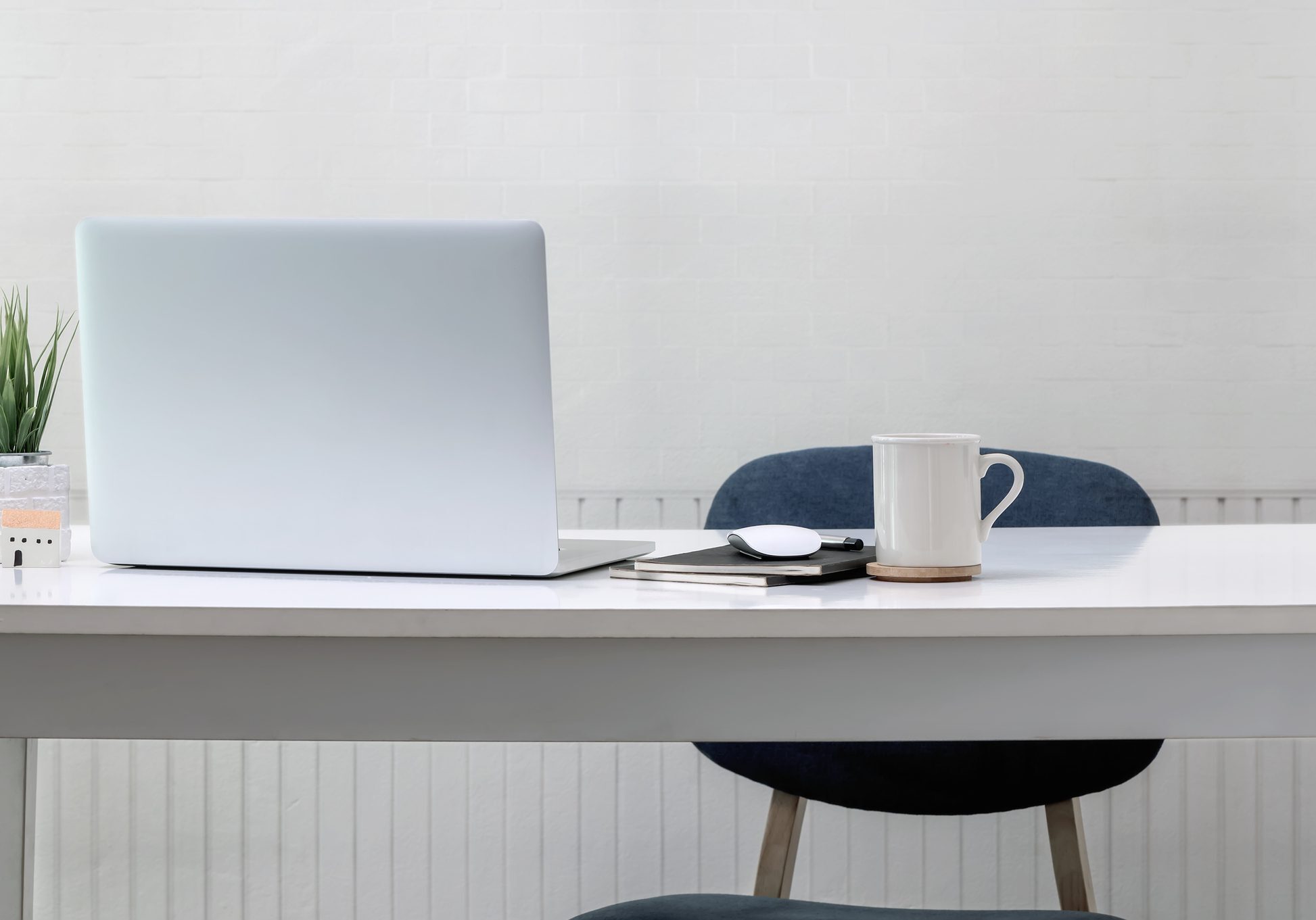 A minimalist workspace with a laptop, coffee mug, and glasses on a wooden table.