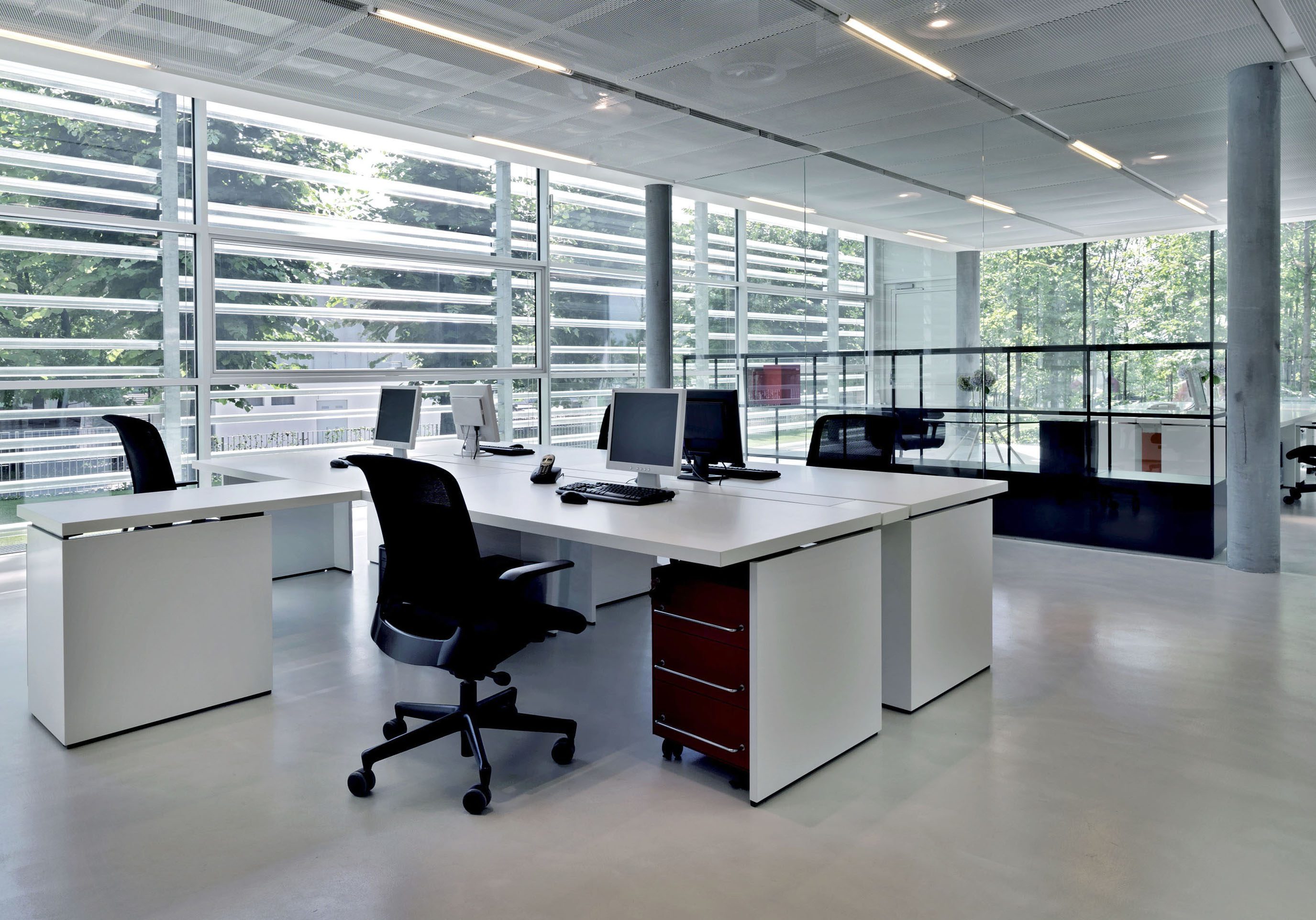 Modern office space with desks, chairs, and large windows.